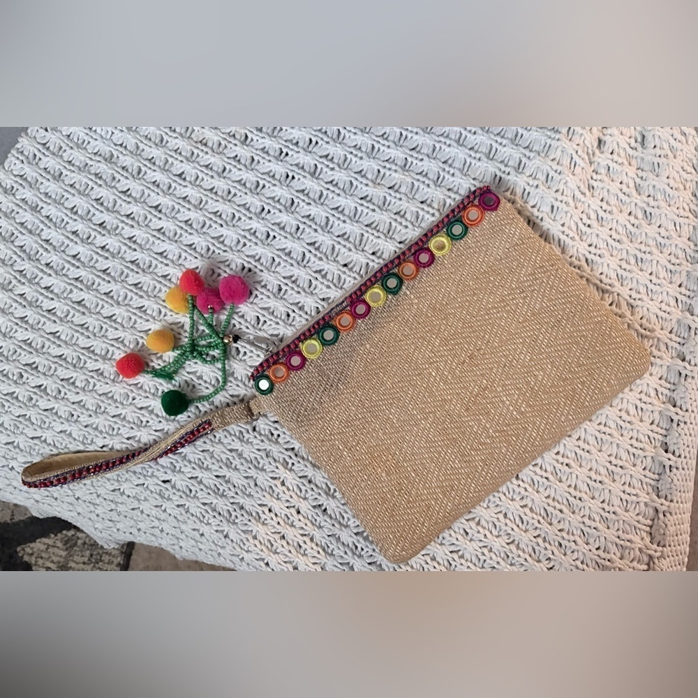 bohemian-style woven clutch jute with pom pom
accents